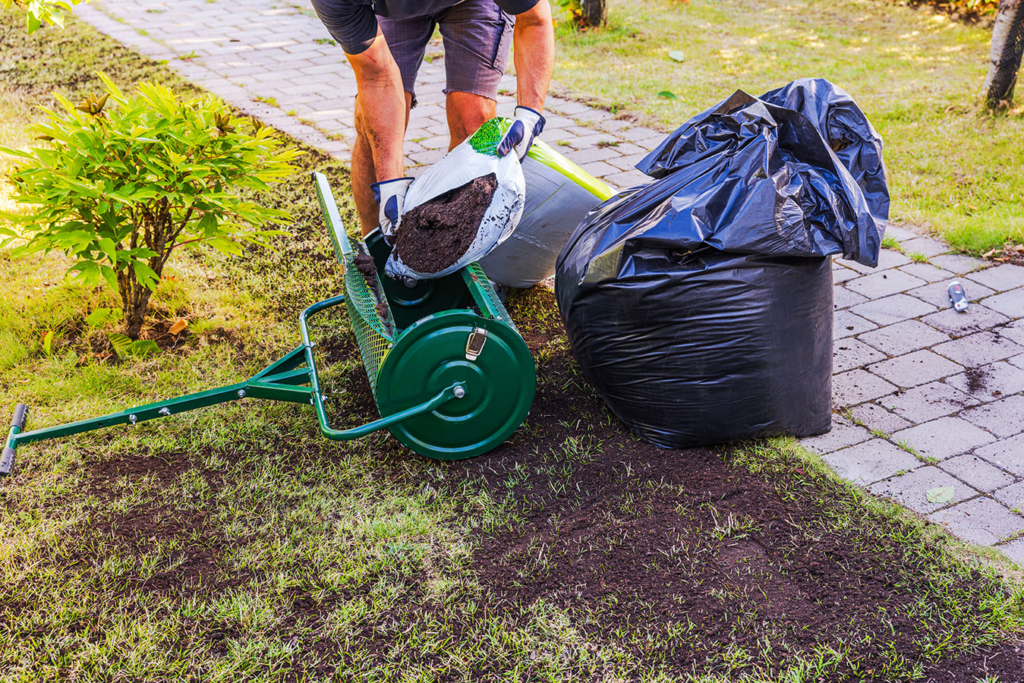 Lawn Care Tips - A man doing lawn care maintenance service with a black garbage bag and a sack