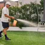 Lawn Care - A man watering a healthy and lush lawn