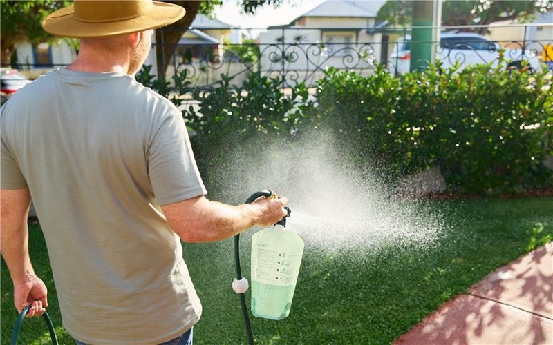 Low-maintenance lawn care - Man watering his lawn with eco friendly lawn care solutions